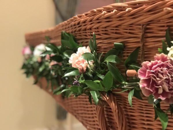 Greenery and flowers on a wicker coffin